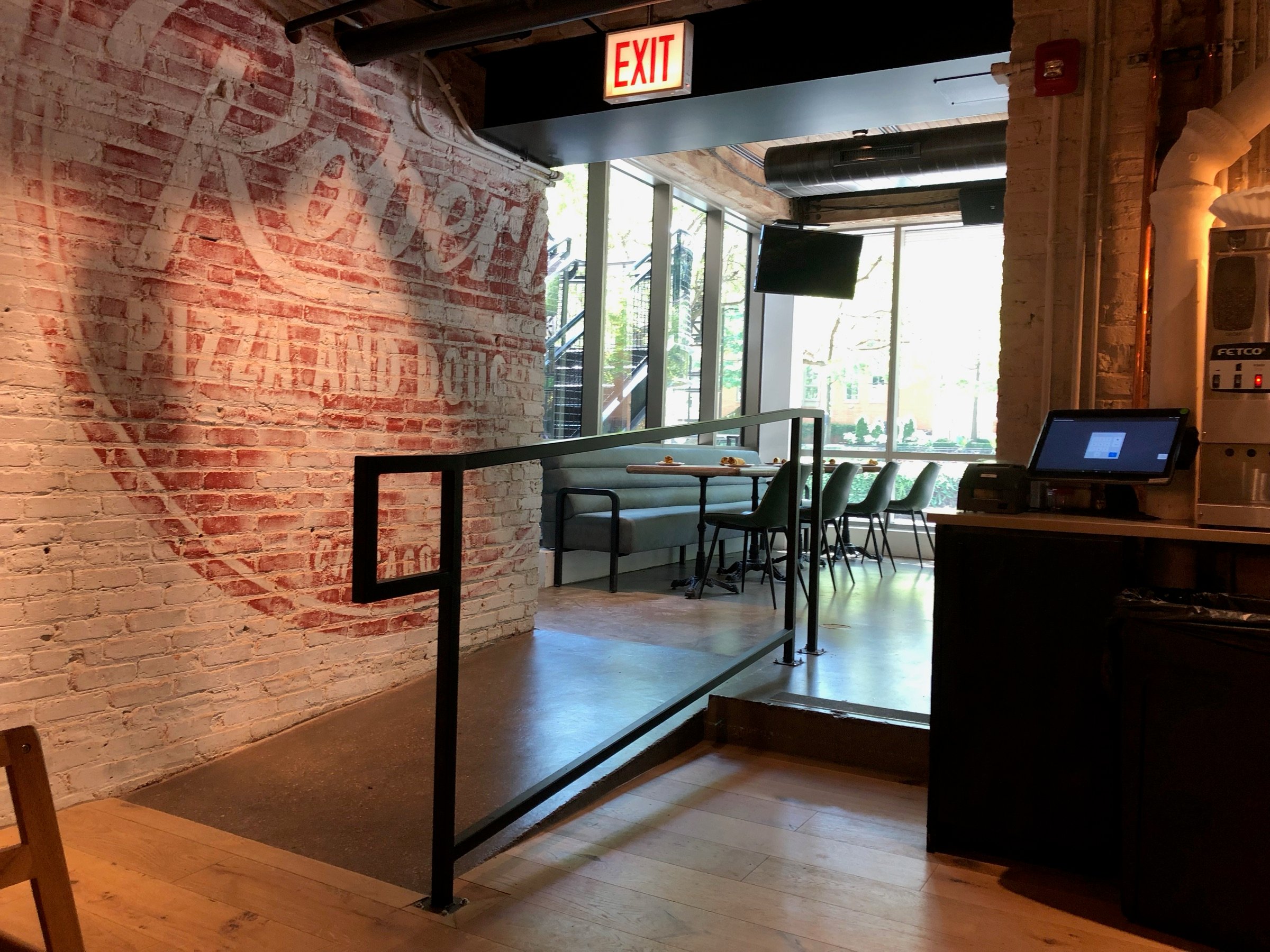 Entry wall with exposed brick and a seated lounge area at Blue Bar