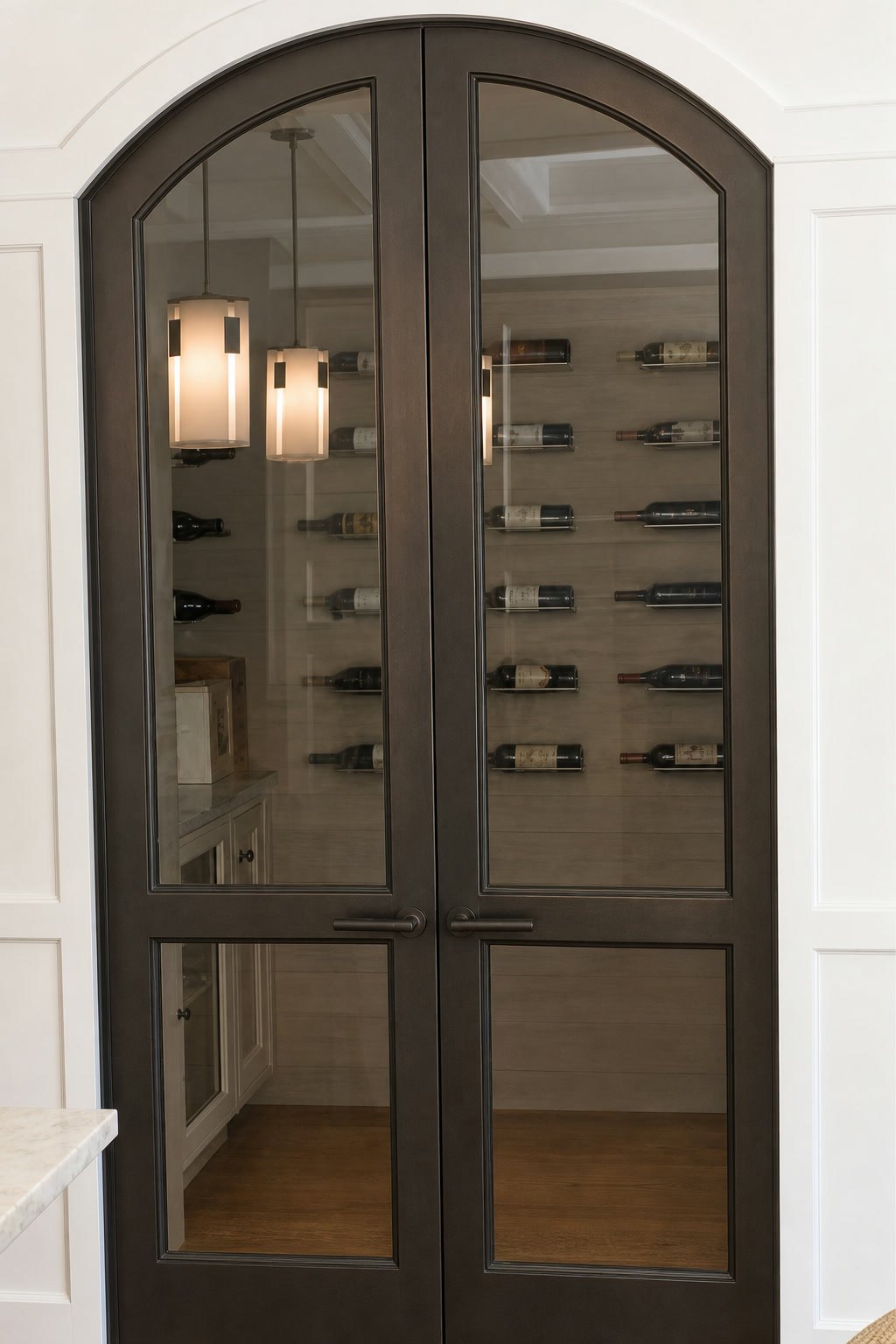 Arched steel-and-glass wine cellar doors with a warm bronze finish