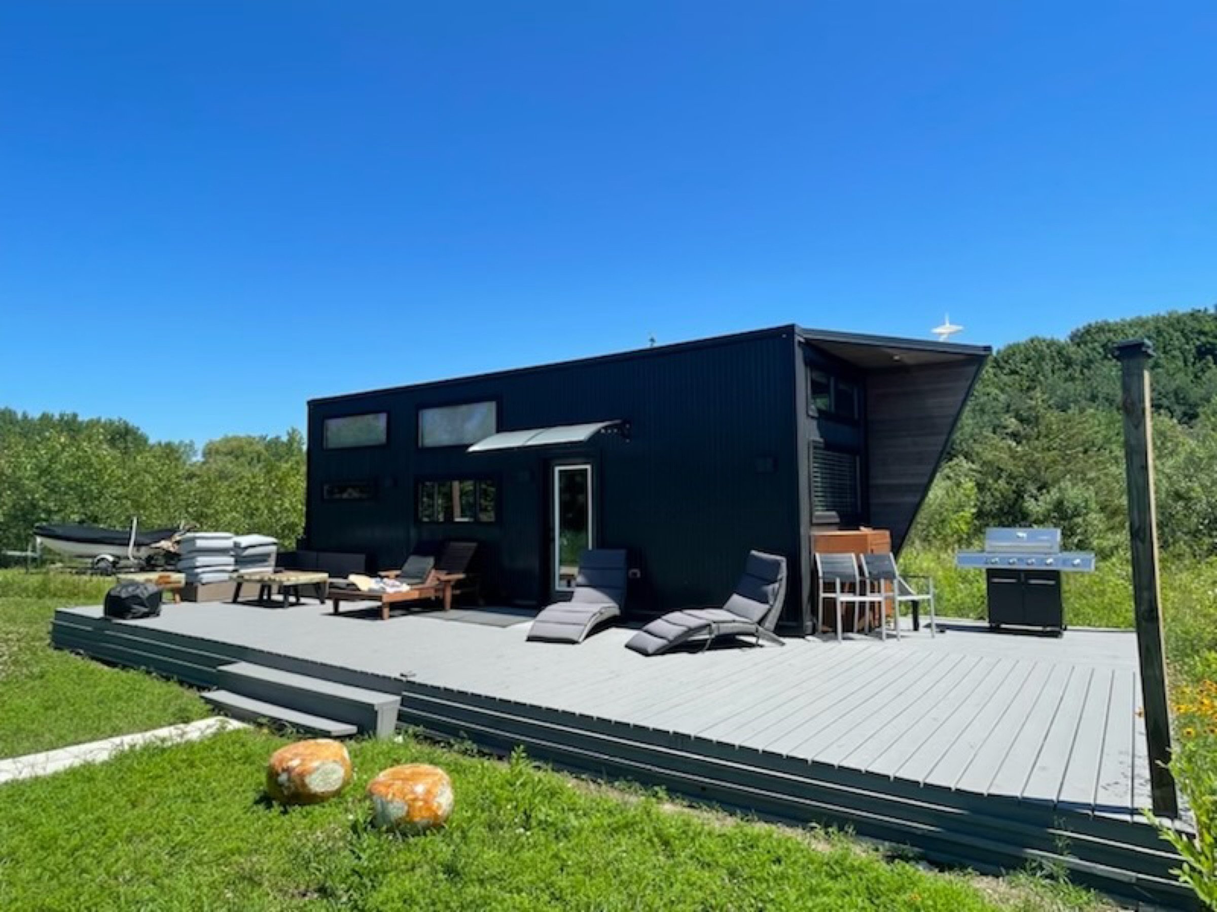Finished exterior deck with lounge seating beside the compact black-clad home