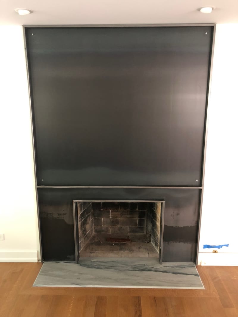 Black steel fireplace surround under installation