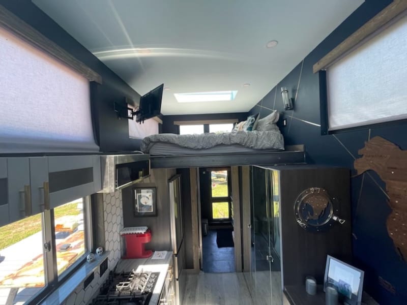 Daylit Mini House interior with lofted sleeping above the compact kitchenette